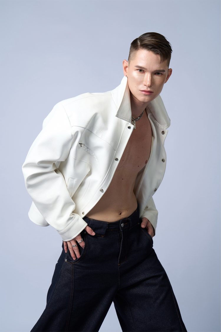 Dee Mak mid-stride in an open white leather jacket, shirtless, hands in denim pockets