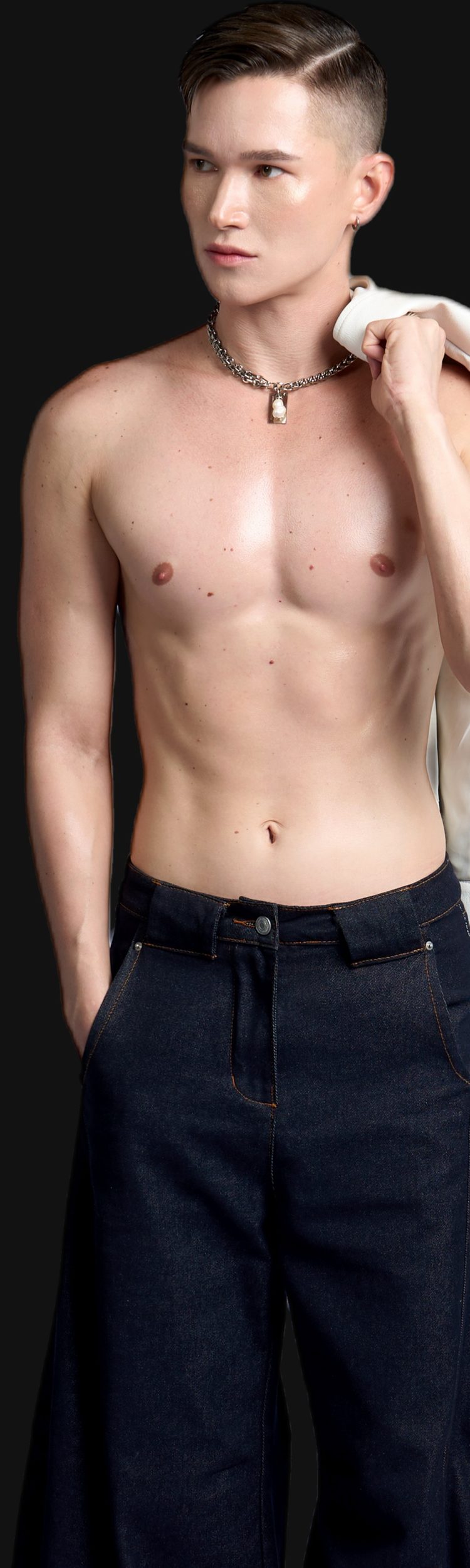 Dee Mak shirtless, wearing a silver chain necklace, holding a white jacket over one shoulder, looking off to the side